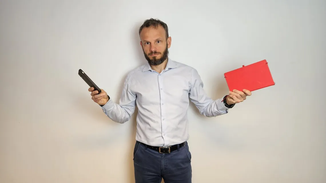 Piotr Szanser trzyma w jednej ręce smartfon, w drugiej tablet: który sprzęt i który program wybrać do spisu